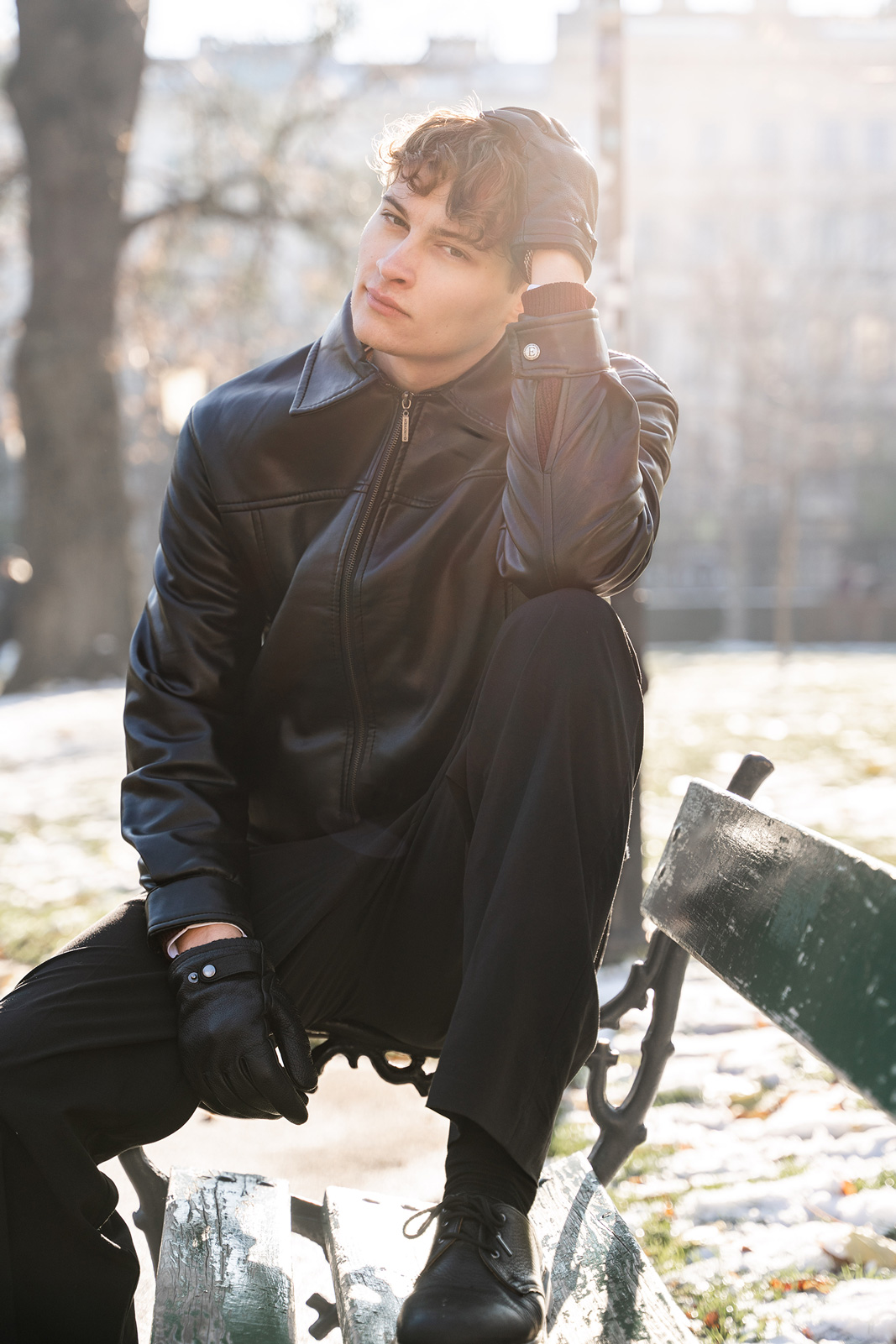 Tobi sitzt auf der Lehne einer alten Parkbank und sieht verträumt in die Kamera