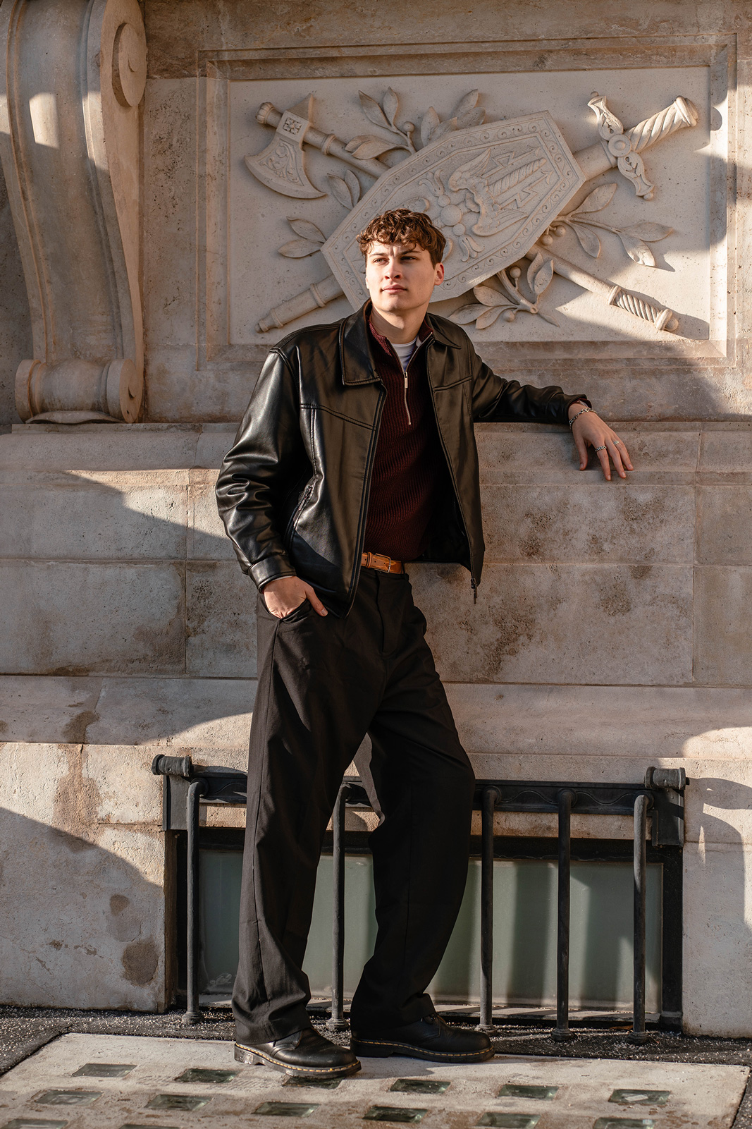 Tobi lehnt lässig vor einem alten Wappen in der Hausmauer im Burggarten