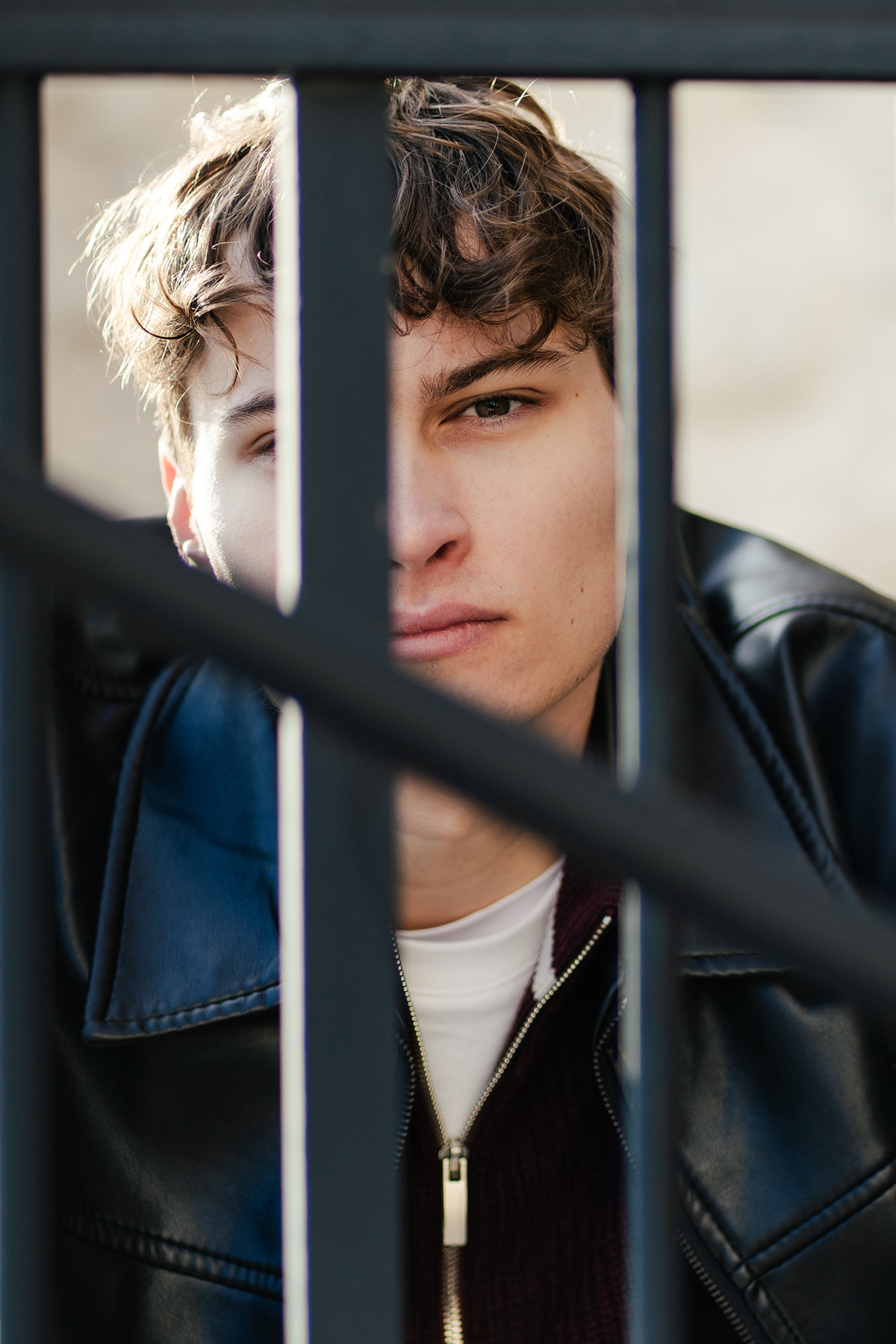 Tobi blickt in die Kamera durch ein paar Metallstangen hindurch