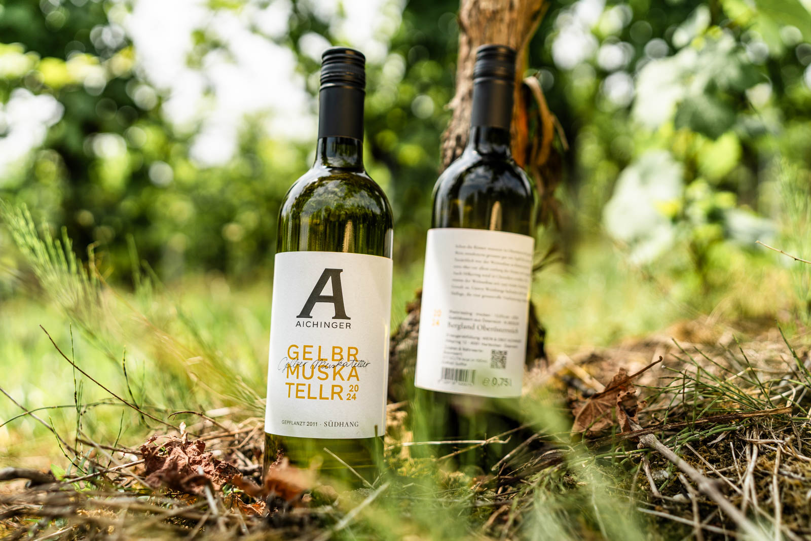 Gelber Muskateller steht neben der Riesling-Flasche, welche so gedreht ist, dass man den Text auf der Rückseite sieht
