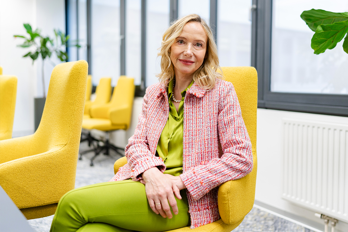 Alexandra Graf sitzt auf einem gelben Bürosessel und schaut in die Kamera