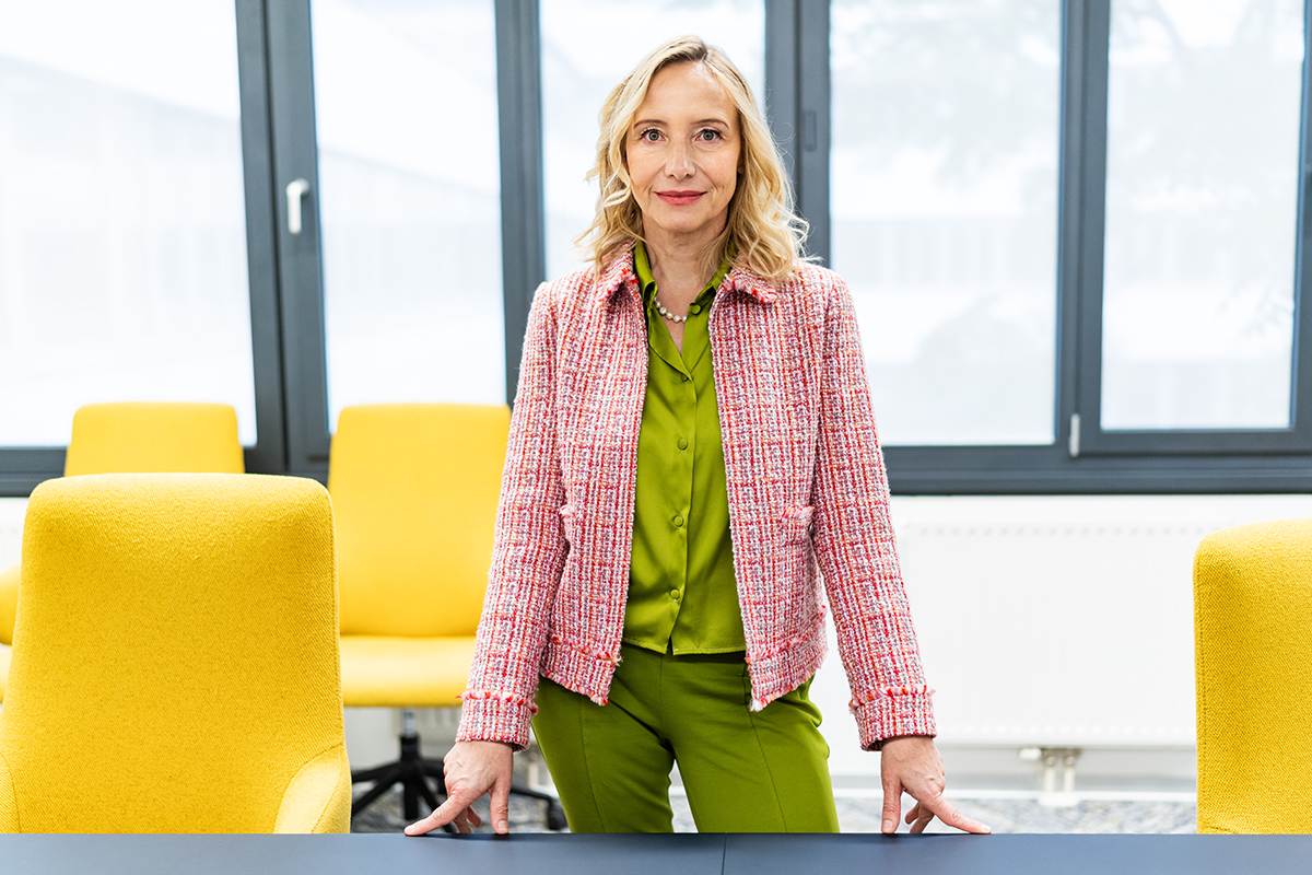 Alexandra Graf steht in einer kompetenten Pose am Tisch im Besprechungsraum