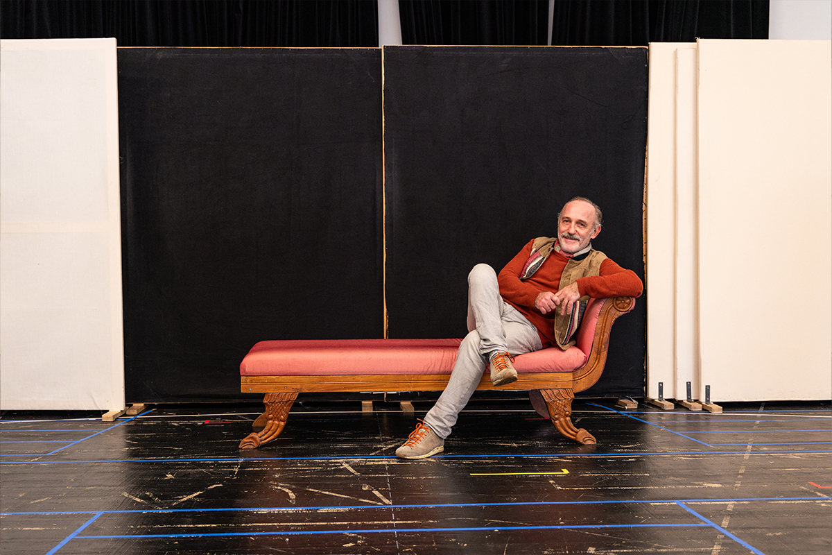 Karl Marcovics sitzt auf einem roten Sofa