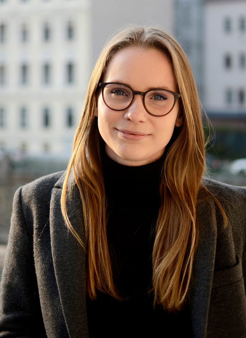 Veronika Seyr mit Brille vor urbanem Hintergrund